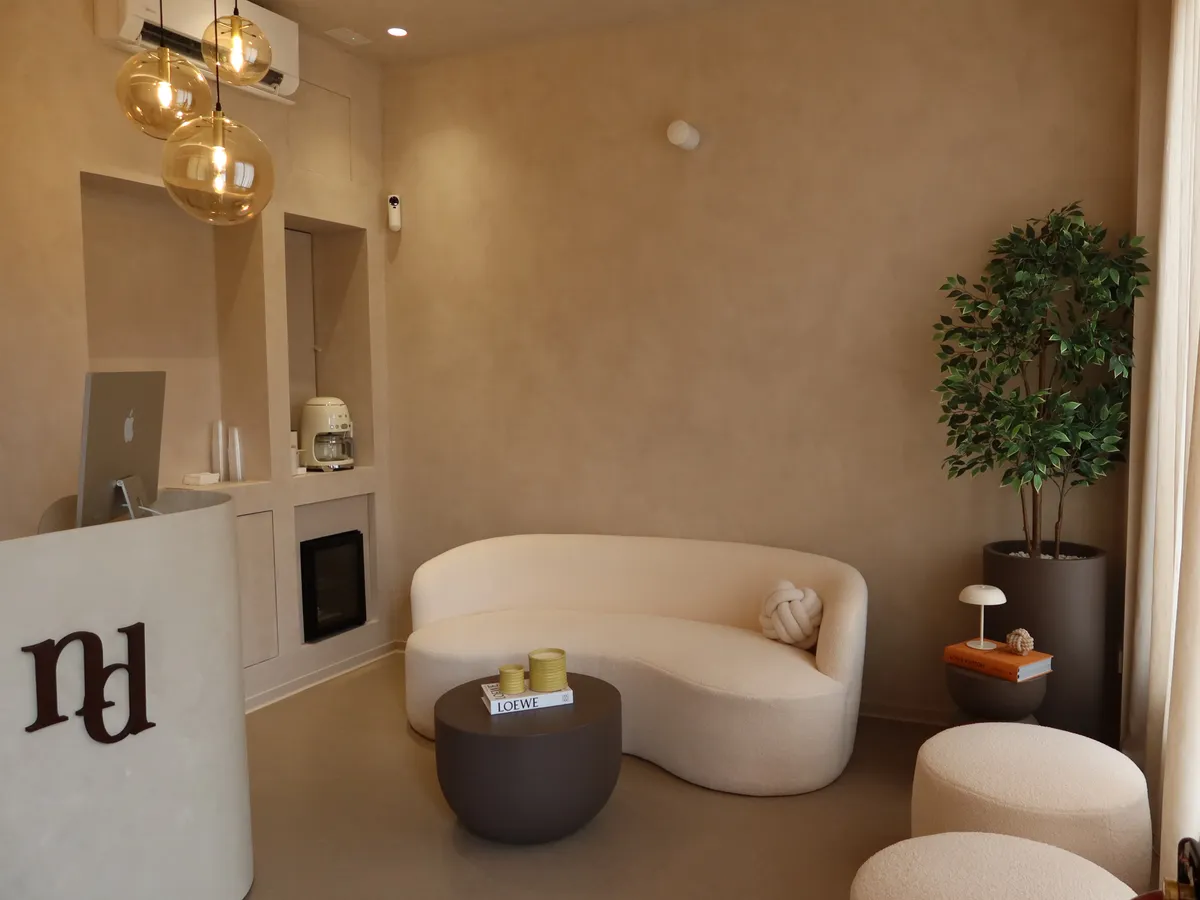 Recepción y zona de espera de Nudhe Studio, con sofá curvo y el monograma del estudio
